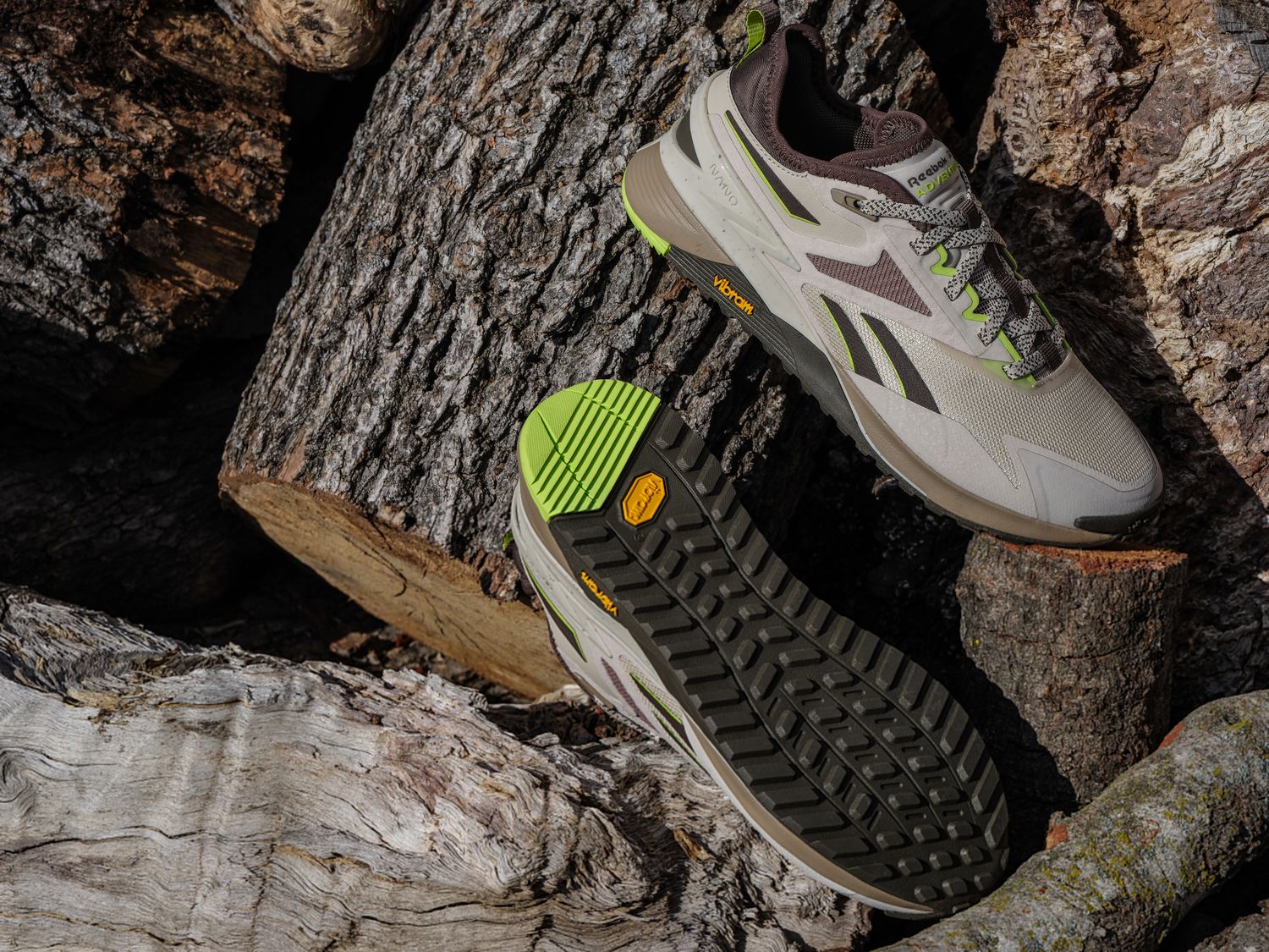 Grey and black Reebok shoes sit on chopped wood.